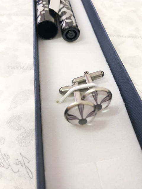 Cufflinks and a black fountain pen with a silver ornament